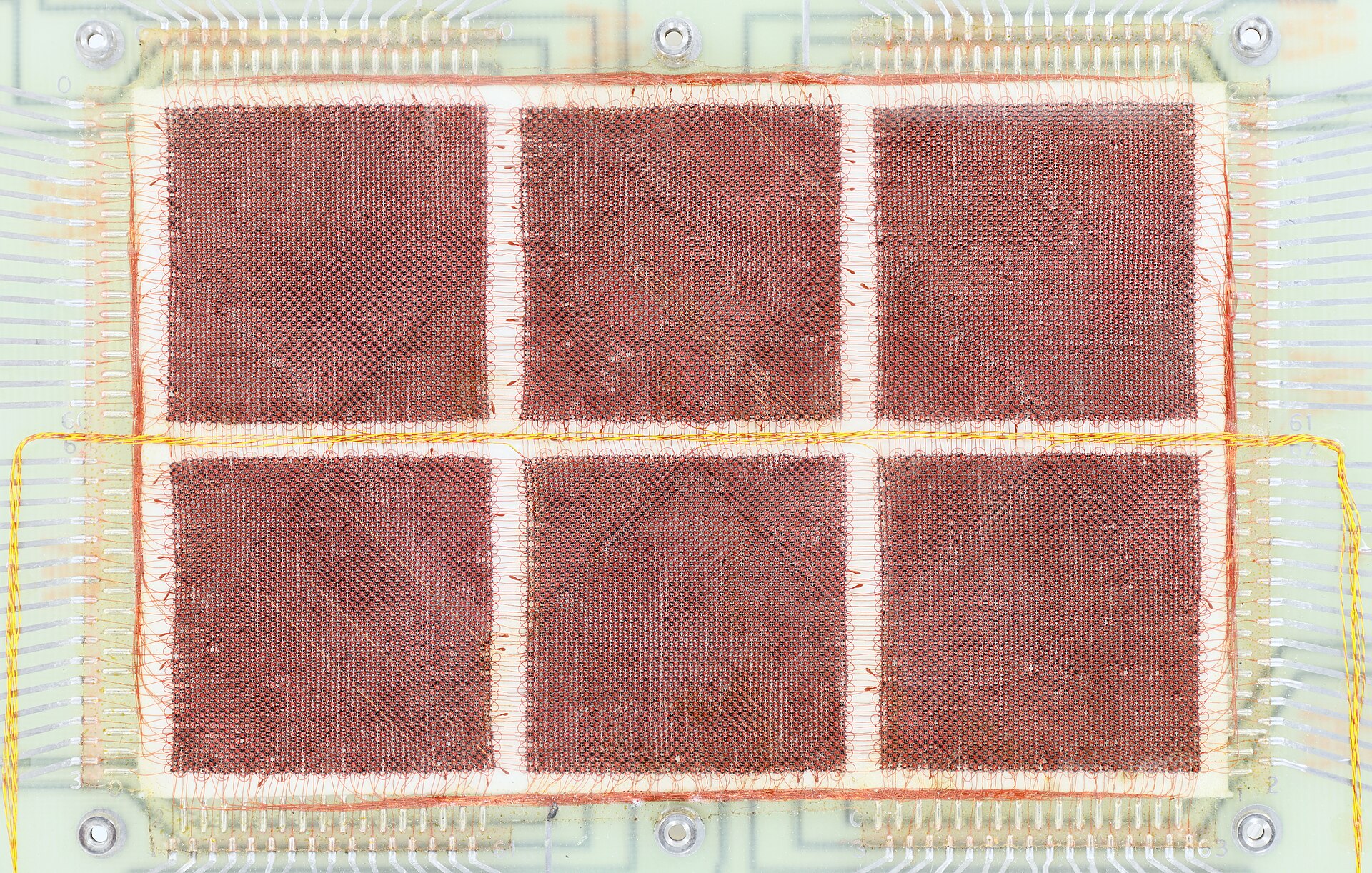 Macro view of six woven magnetic-core memory planes wired with copper sense lines on a ceramic module